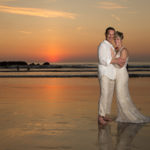 Newly wedded couple in front of an ocean sunset
